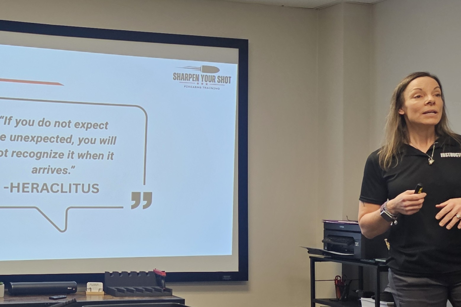 Firearms instructor teaching a class with a mental preparedness quote displayed behind her